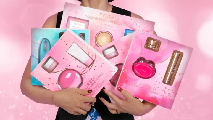 A woman holding a lot of FOREO skincare sets as ideal holiday gifts